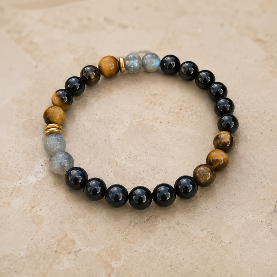 Bracelet en tourmaline noire, labradorite et œil de tigre sur une surface beige naturelle