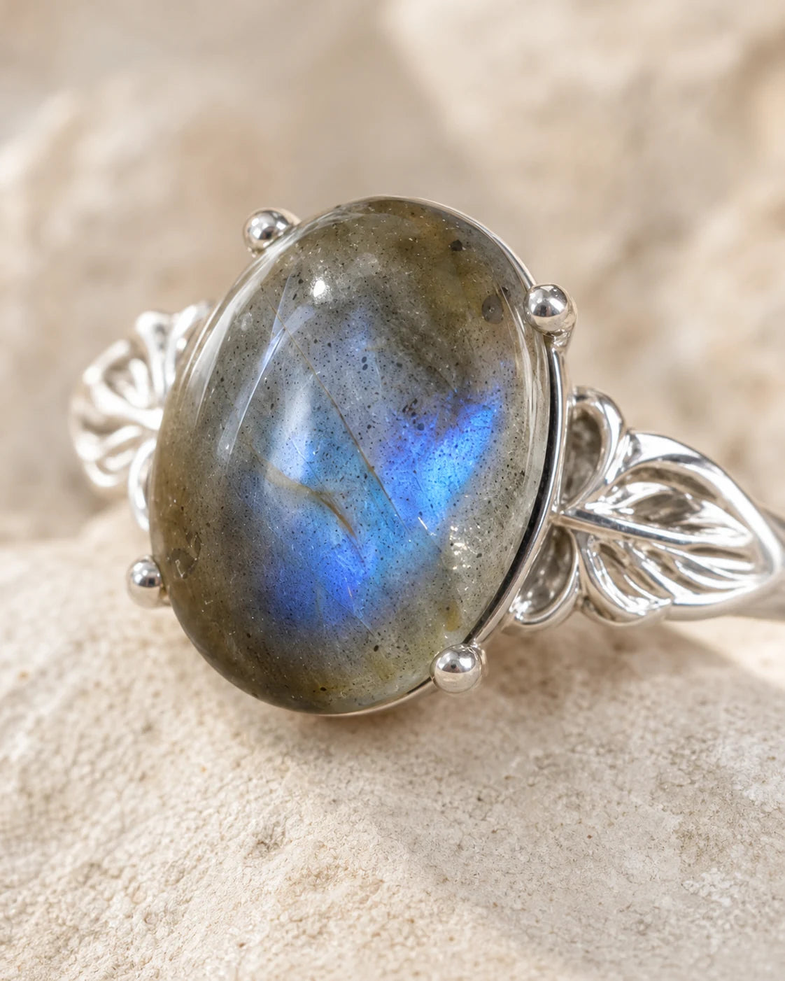 Gros plan sur la labradorite ovale et le sertissage argenté de la bague