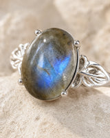 Gros plan sur la labradorite ovale et le sertissage argenté de la bague