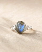 Bague réglable en labradorite ovale aux reflets bleu-gris sur pierre beige