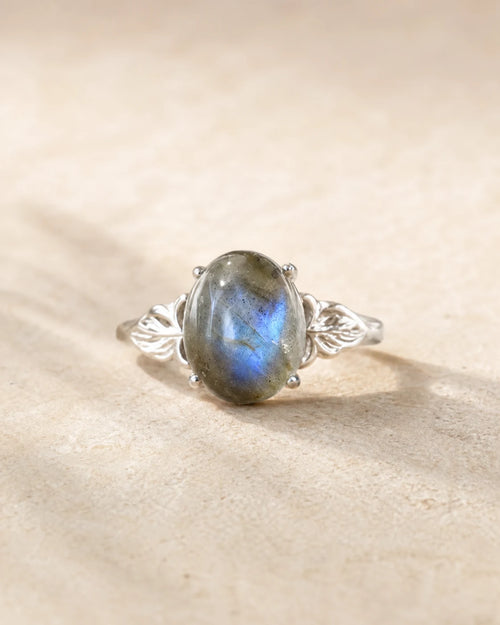 Bague réglable en labradorite ovale aux reflets bleu-gris sur pierre beige