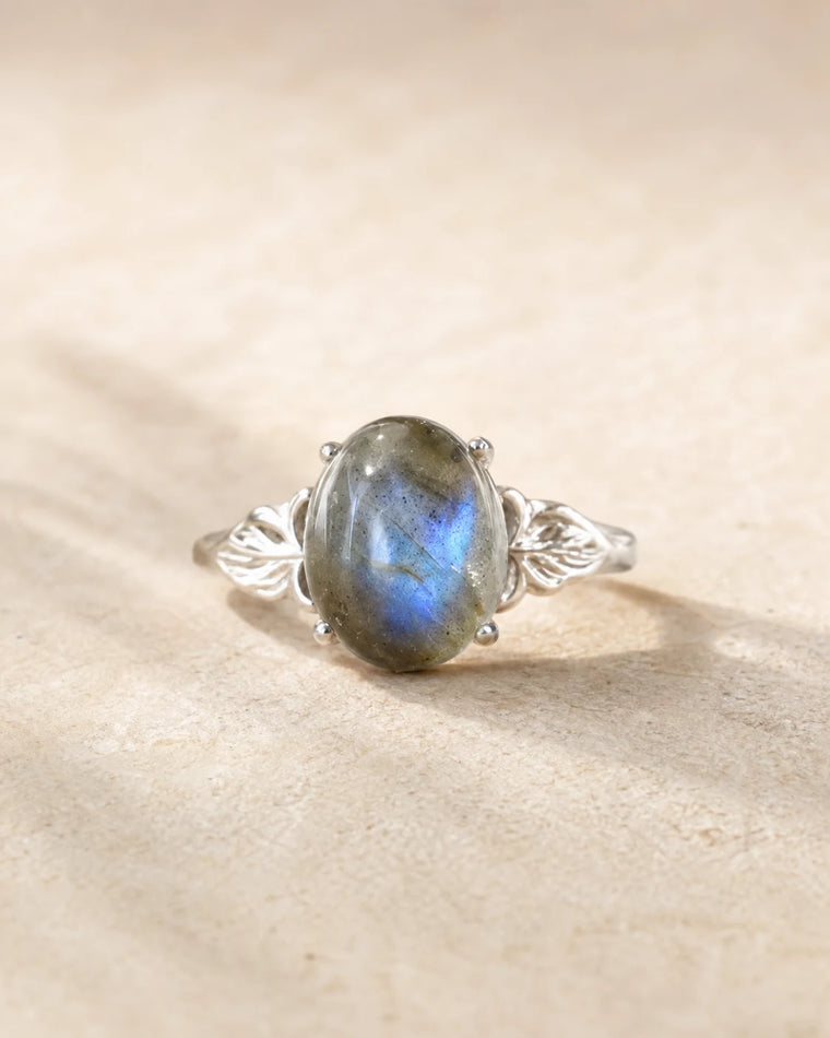 Bague réglable en labradorite ovale aux reflets bleu-gris sur pierre beige