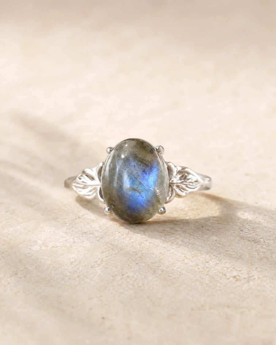 Bague réglable en labradorite ovale aux reflets bleu-gris sur pierre beige