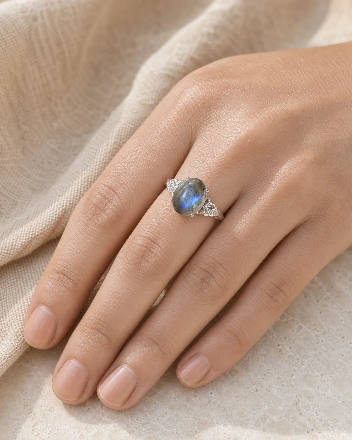 Bague réglable en labradorite portée sur une main aux ongles naturels