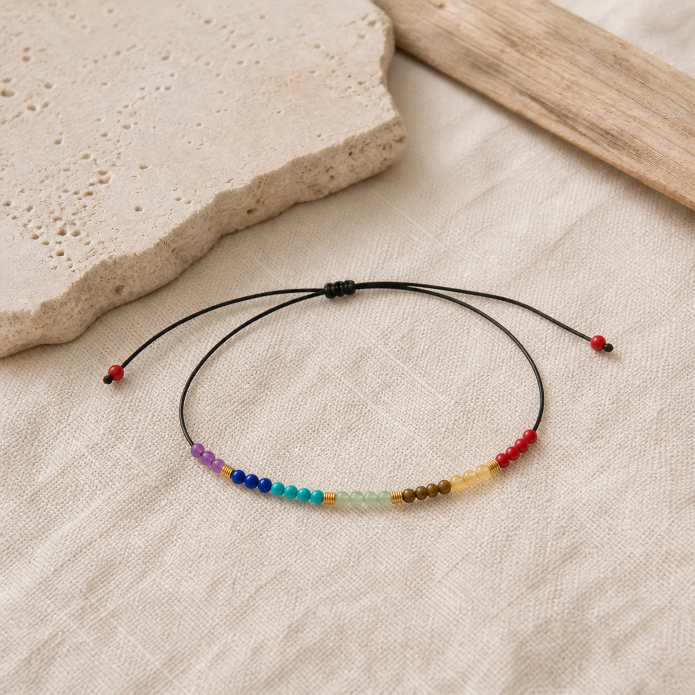 Bracelet 7 Chakras fin en pierres naturelles présenté sur du lin clair.