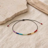 Bracelet 7 Chakras fin en pierres naturelles présenté sur du lin clair.