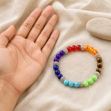 Bracelet 7 Chakras présenté à côté d’une main pour montrer l’échelle des perles.