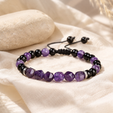 Bracelet en améthyste violette et onyx noir posé sur un tissu en lin beige naturel