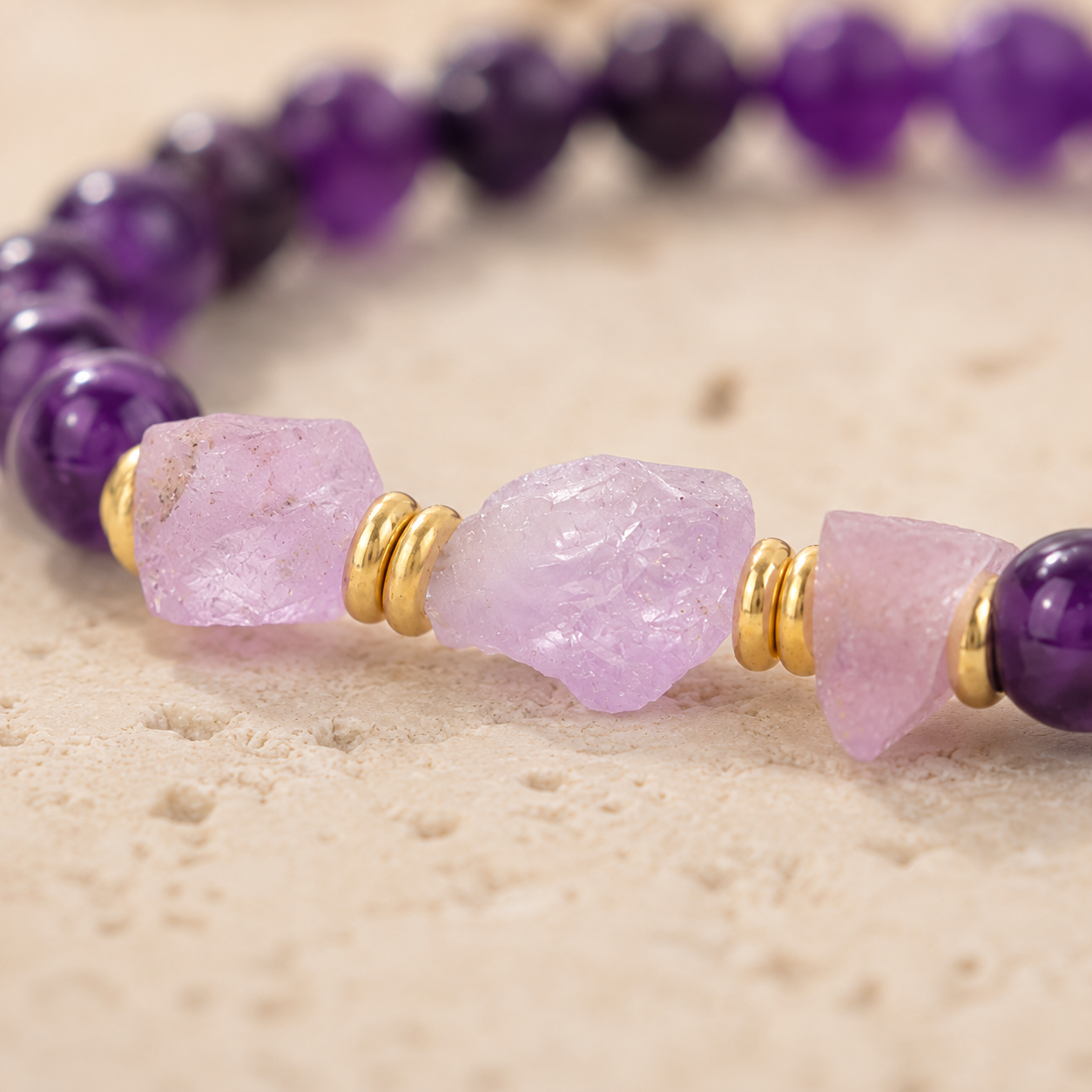 Gros plan sur les pierres brutes et les perles violettes du bracelet Elara