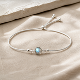 Bracelet minimaliste en argent 925 avec pierre de lune ronde sur lin clair.