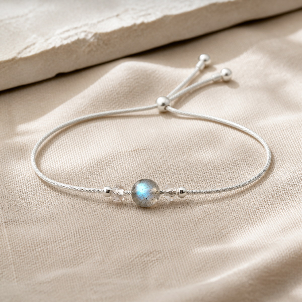 Bracelet minimaliste en argent 925 avec pierre de lune ronde sur lin clair.