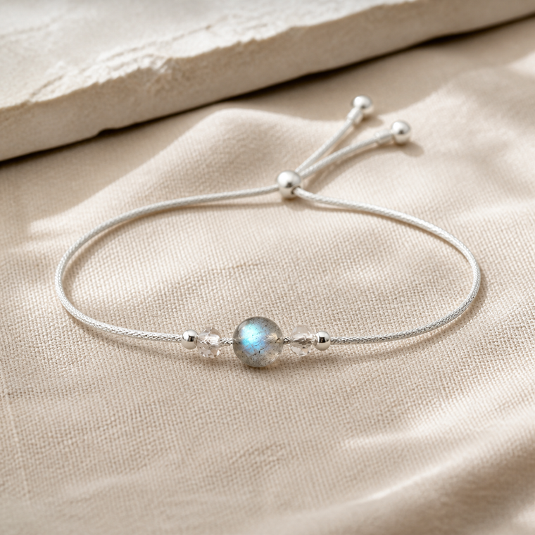 Bracelet minimaliste en argent 925 avec pierre de lune ronde sur lin clair.