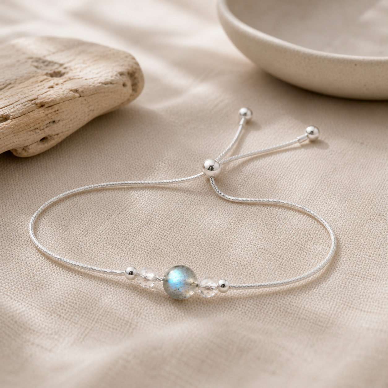 Bracelet en argent 925 et pierre de lune présenté sur lin et bois clair.