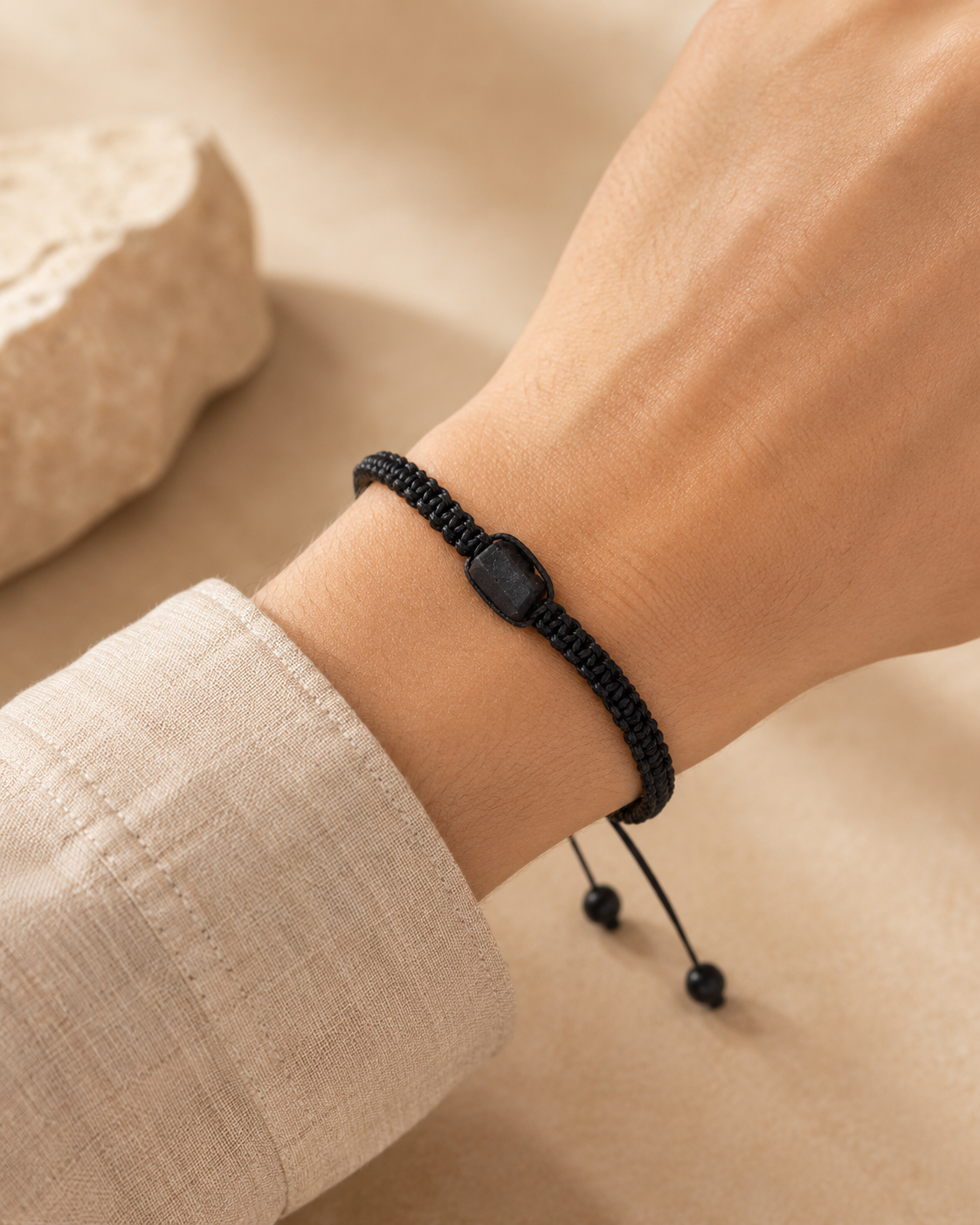 Bracelet minimaliste en tourmaline noire brute porté au poignet avec une manche en lin clair.