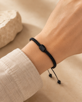 Bracelet minimaliste en tourmaline noire brute porté au poignet avec une manche en lin clair.