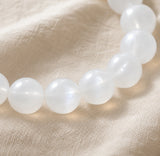 Détail des perles polies et laiteuses du bracelet en pierre de lune blanche.