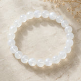 Vue complète du bracelet en perles blanches de pierre de lune sur une surface claire.