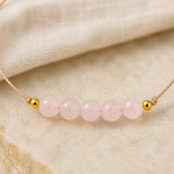 Détail des pierres de quartz rose d’un bracelet à cordon fin.