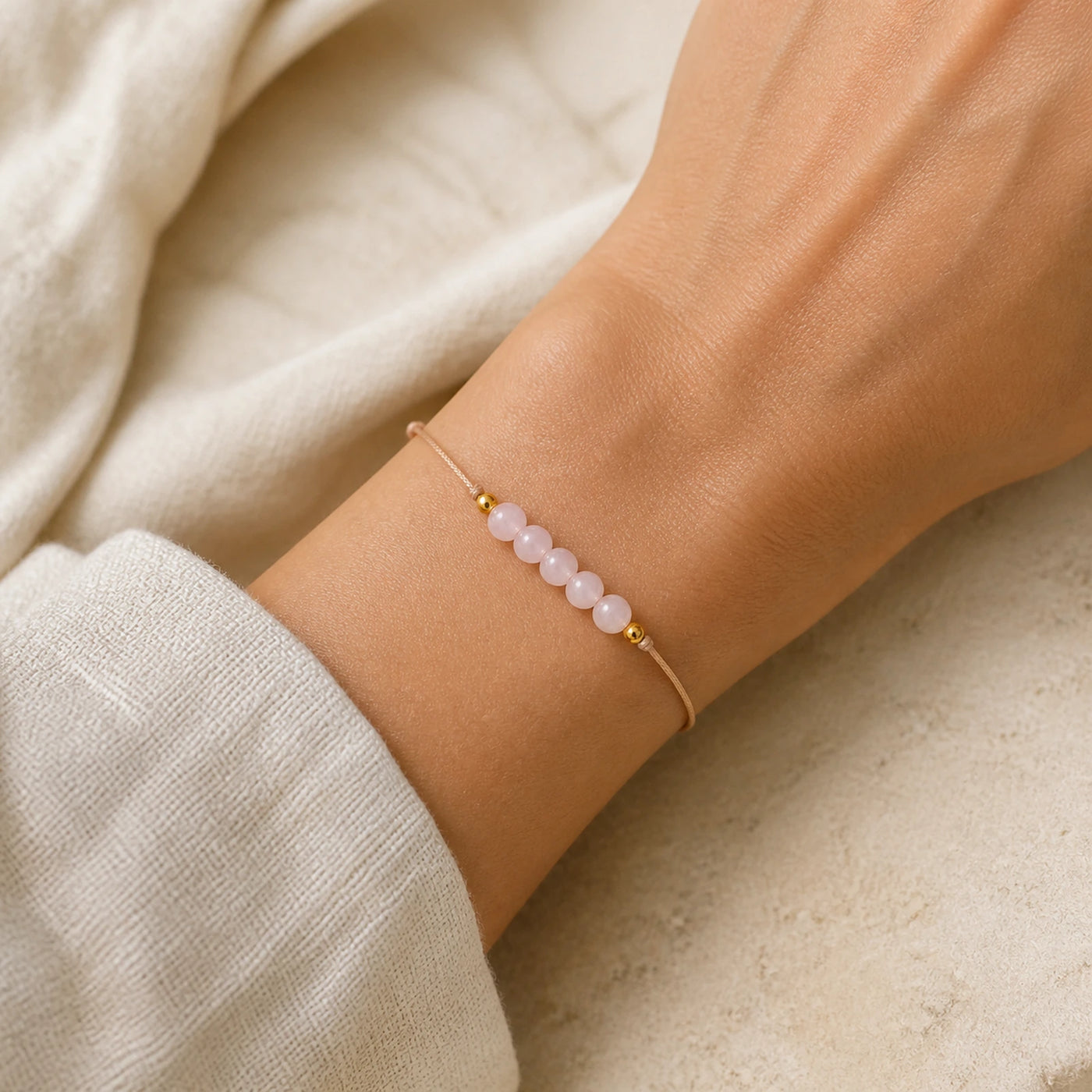 Bracelet en quartz rose à cordon ajustable porté au poignet.