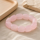Bracelet en quartz rose naturel présenté sur du lin clair.