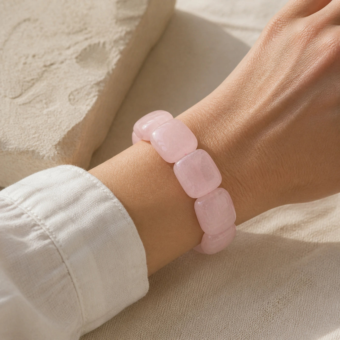 Bracelet en grosses perles de quartz rose porté au poignet.