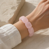 Bracelet en grosses perles de quartz rose porté au poignet.