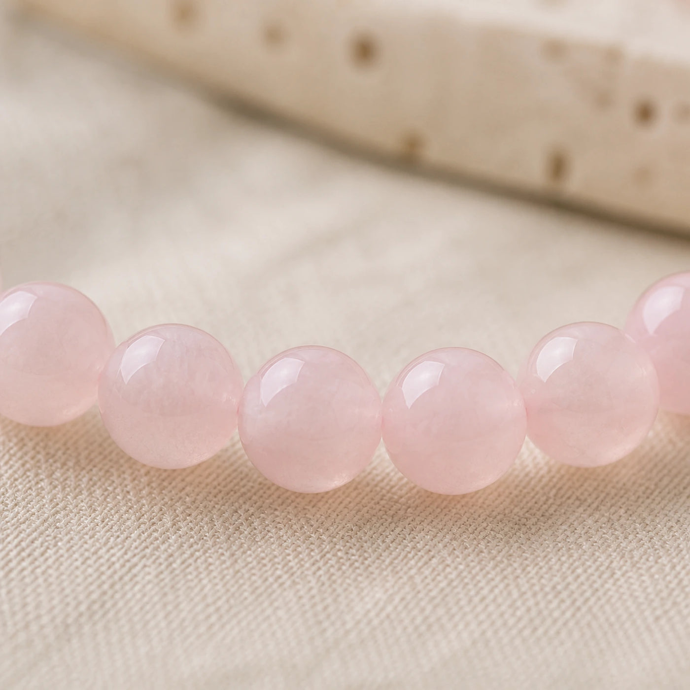 Détail des nuances naturelles de perles en quartz rose poli.