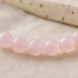 Détail des nuances naturelles de perles en quartz rose poli.
