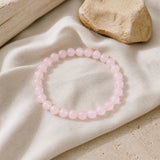 Bracelet en perles de quartz rose naturel présenté sur du lin clair.