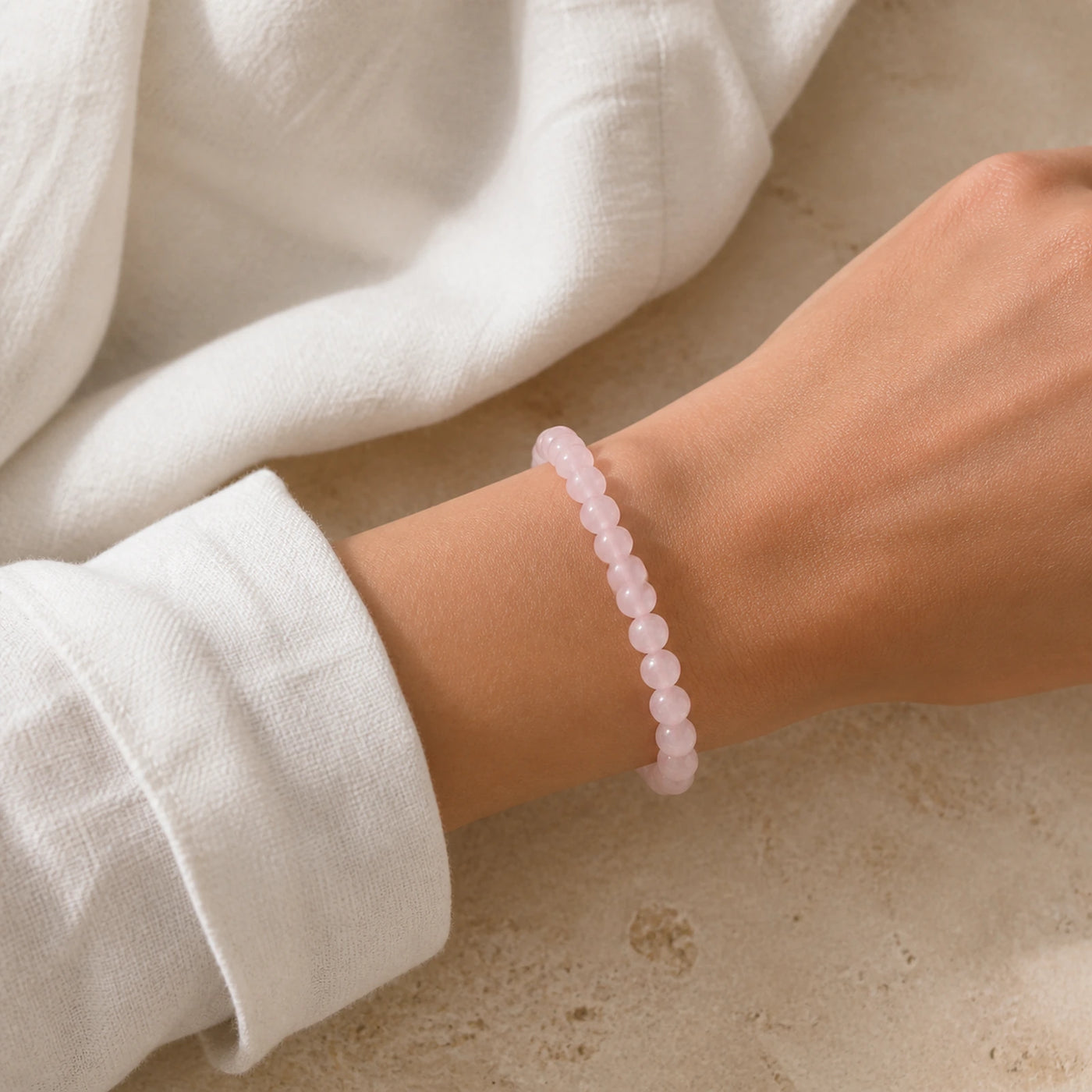 Bracelet en quartz rose à perles de 8 mm porté au poignet.