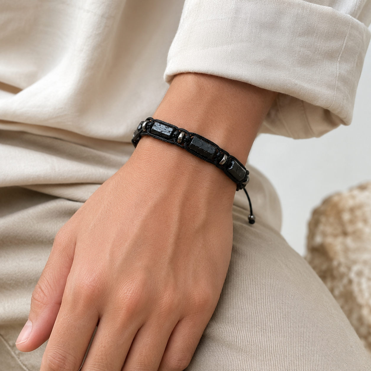 Bracelet en tourmaline noire brute porté au poignet avec une tenue en lin clair