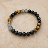 Bracelet en tourmaline noire, labradorite et œil de tigre sur une surface beige naturelle