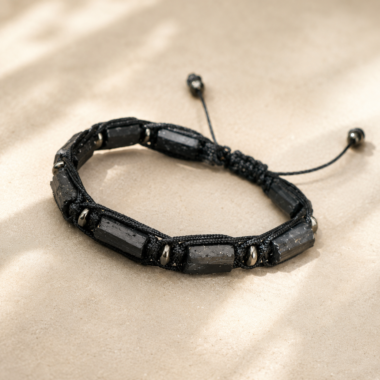 Bracelet en tourmaline noire brute sur cordon tressé, vue principale sur fond minéral beige