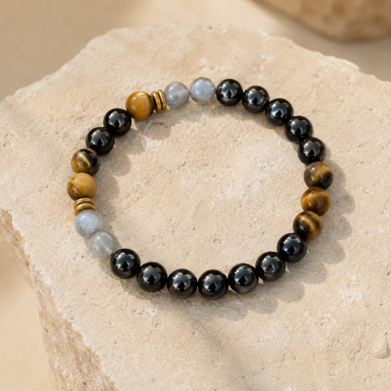 Bracelet en tourmaline noire et pierres naturelles présenté sur une pierre beige