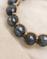 Gros plan sur les perles sombres en labradorite et le tressage beige