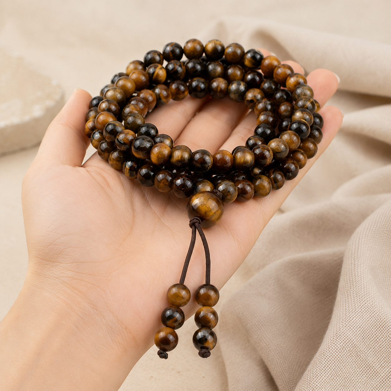 Mala 108 perles en œil de tigre tenu en main