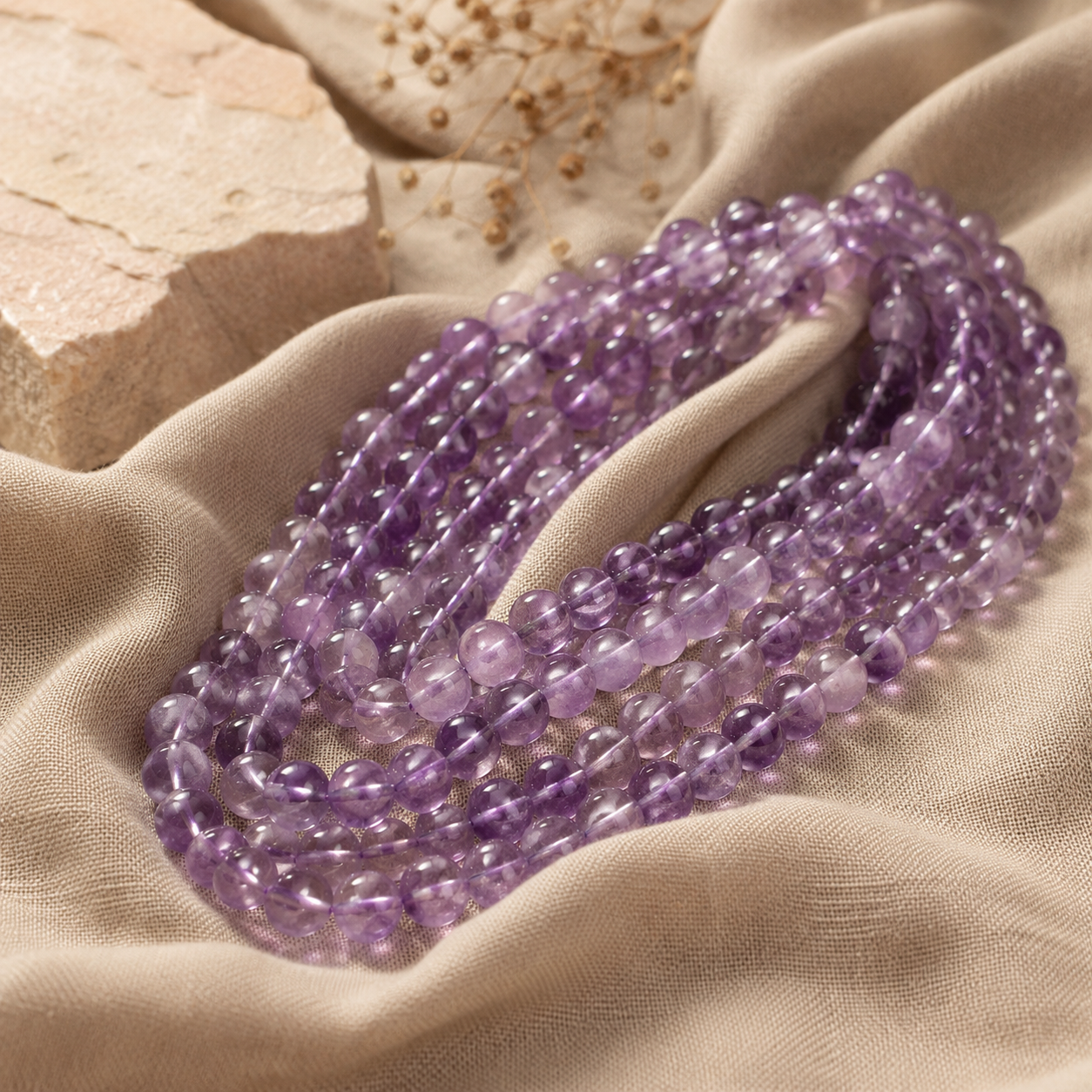 Rangées de perles d’améthyste violettes posées sur un tissu en lin naturel