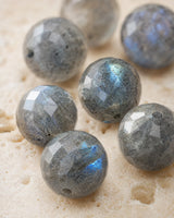 Gros plan sur les facettes et les reflets bleu-gris de perles en labradorite