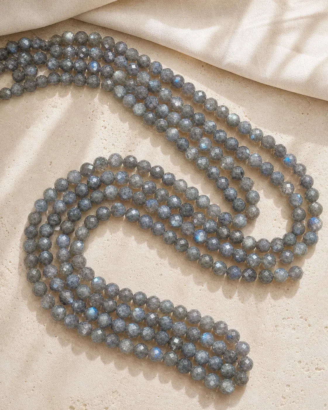 Vue complète d’un lot de perles facettées en labradorite sur lin clair