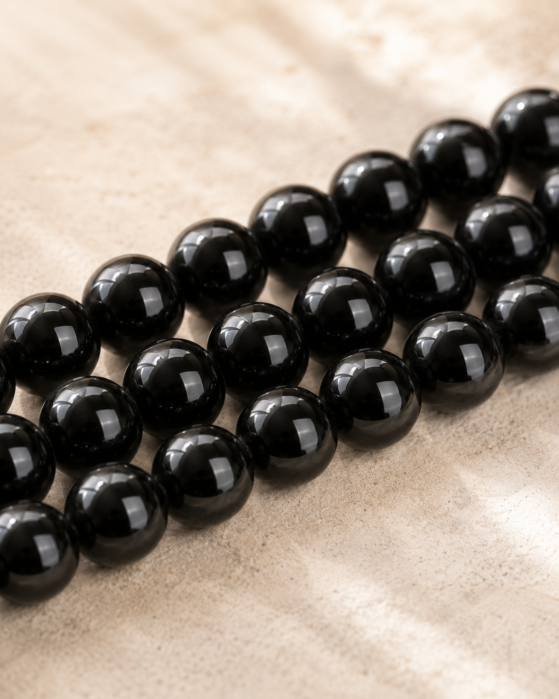 Gros plan sur des perles rondes de tourmaline noire naturelle aux reflets brillants.