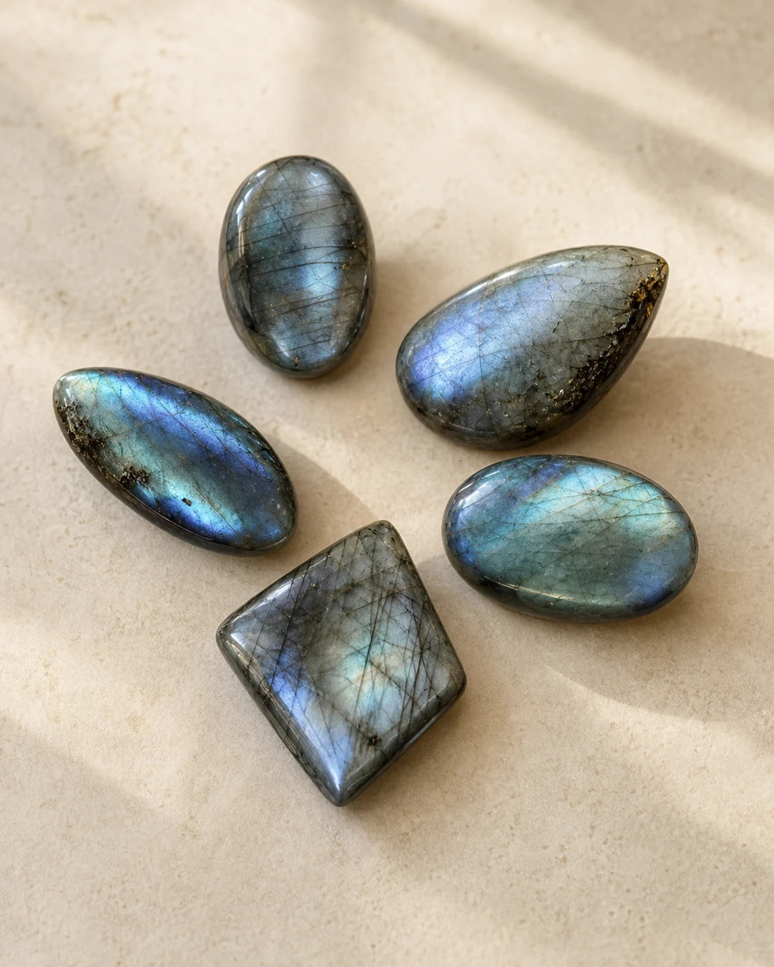 Lot de cinq pierres polies en labradorite sur pierre beige
