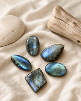 Cinq pierres polies en labradorite sur lin clair, pierre naturelle et bois brut