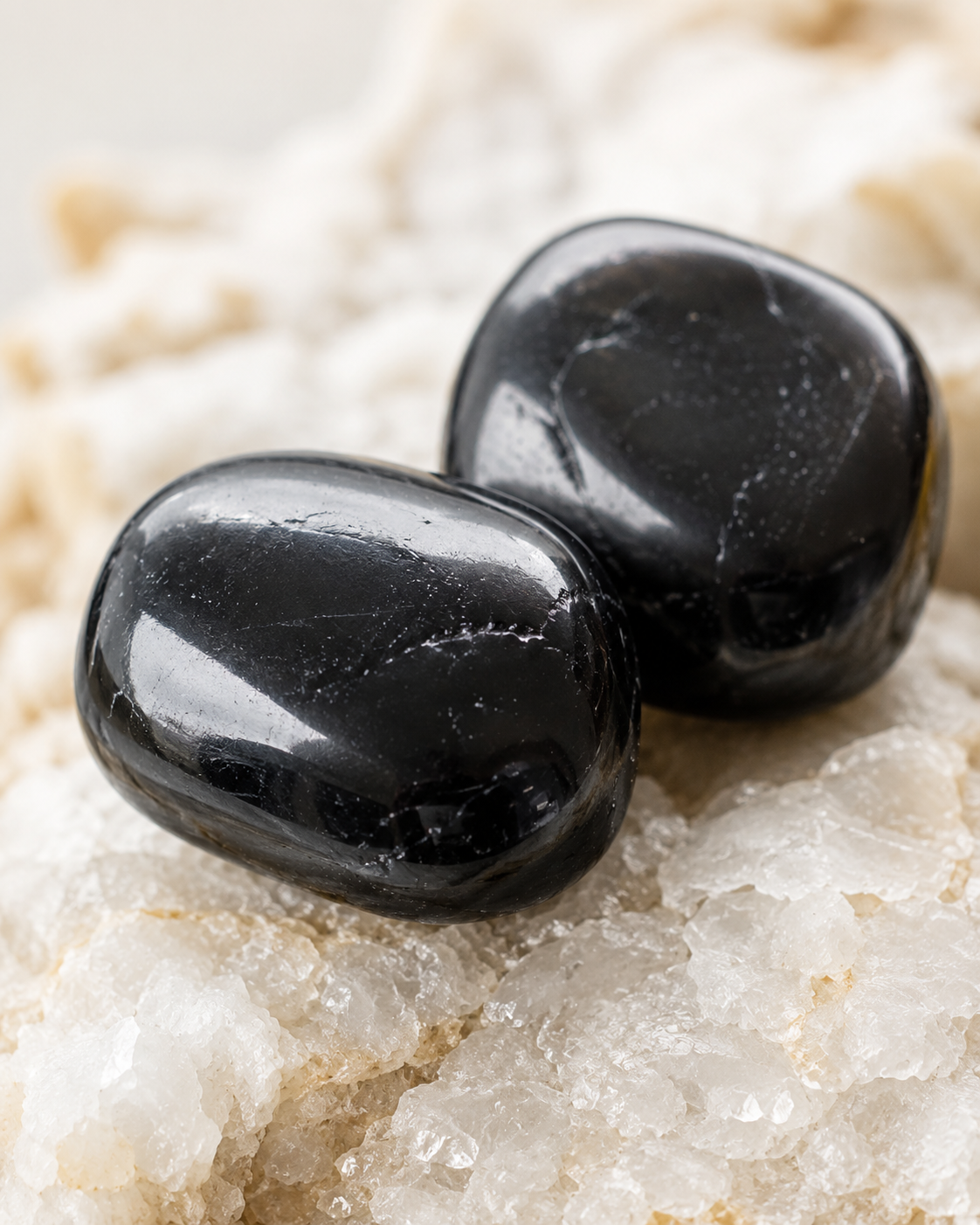 Gros plan sur deux pierres roulées de tourmaline noire naturelle aux reflets lisses et brillants.