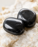 Gros plan sur deux pierres roulées de tourmaline noire naturelle aux reflets lisses et brillants.