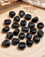 Ensemble de pierres roulées de tourmaline noire naturelle présenté sur un plateau en bois clair.
