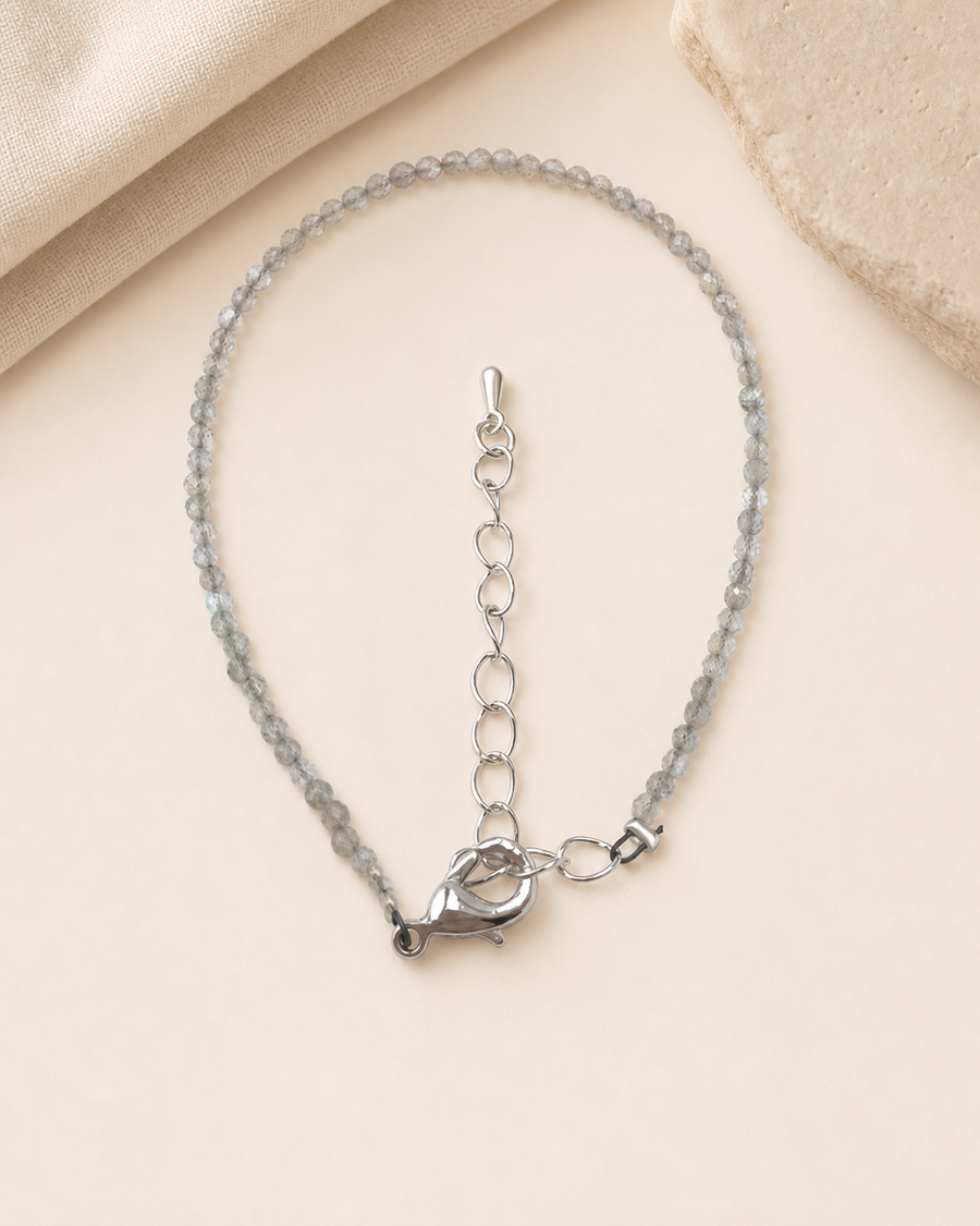 Bracelet fin en labradorite facettée sur fond beige