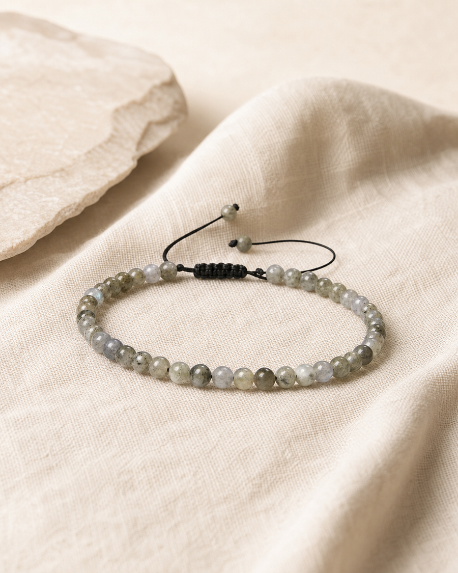 Bracelet minimaliste en labradorite sur lin clair, avec cordon noir ajustable.