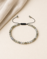 Vue complète d’un bracelet minimaliste en labradorite avec cordon noir ajustable.